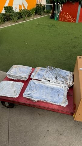 Foil trays of meals arranged on a red cart outdoors