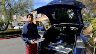 Vinay loading meal trays into a car trunk for delivery
