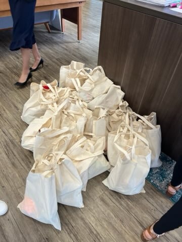 Canvas tote bags filled with meals piled on an office floor