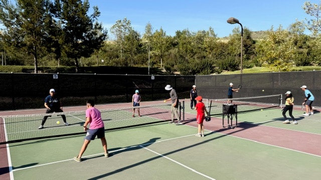Participants of all ages enjoying a pickleball clinic on outdoor courts